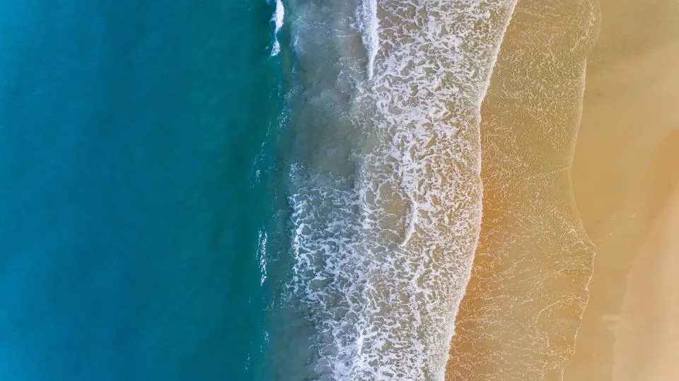 Vista aérea del océano, olas rompiendo sobre la arena